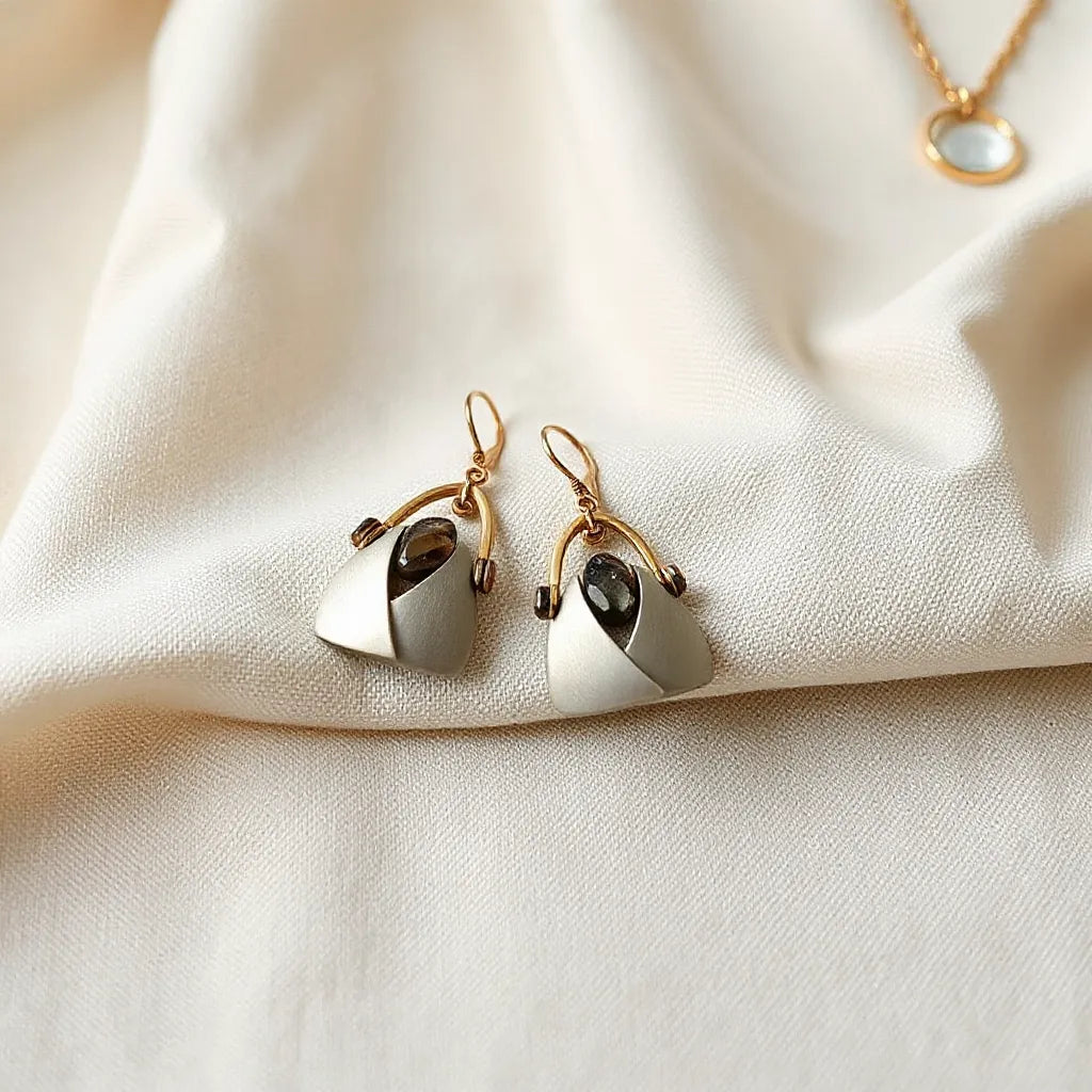 Pair of distinctive geometric earrings on neutral fabric with soft natural light