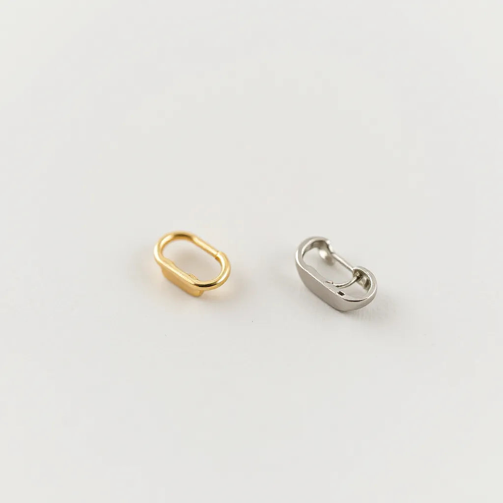 Gold-tone and silver-tone clip-on earrings resting on a neutral surface with visible cushioned clip backs