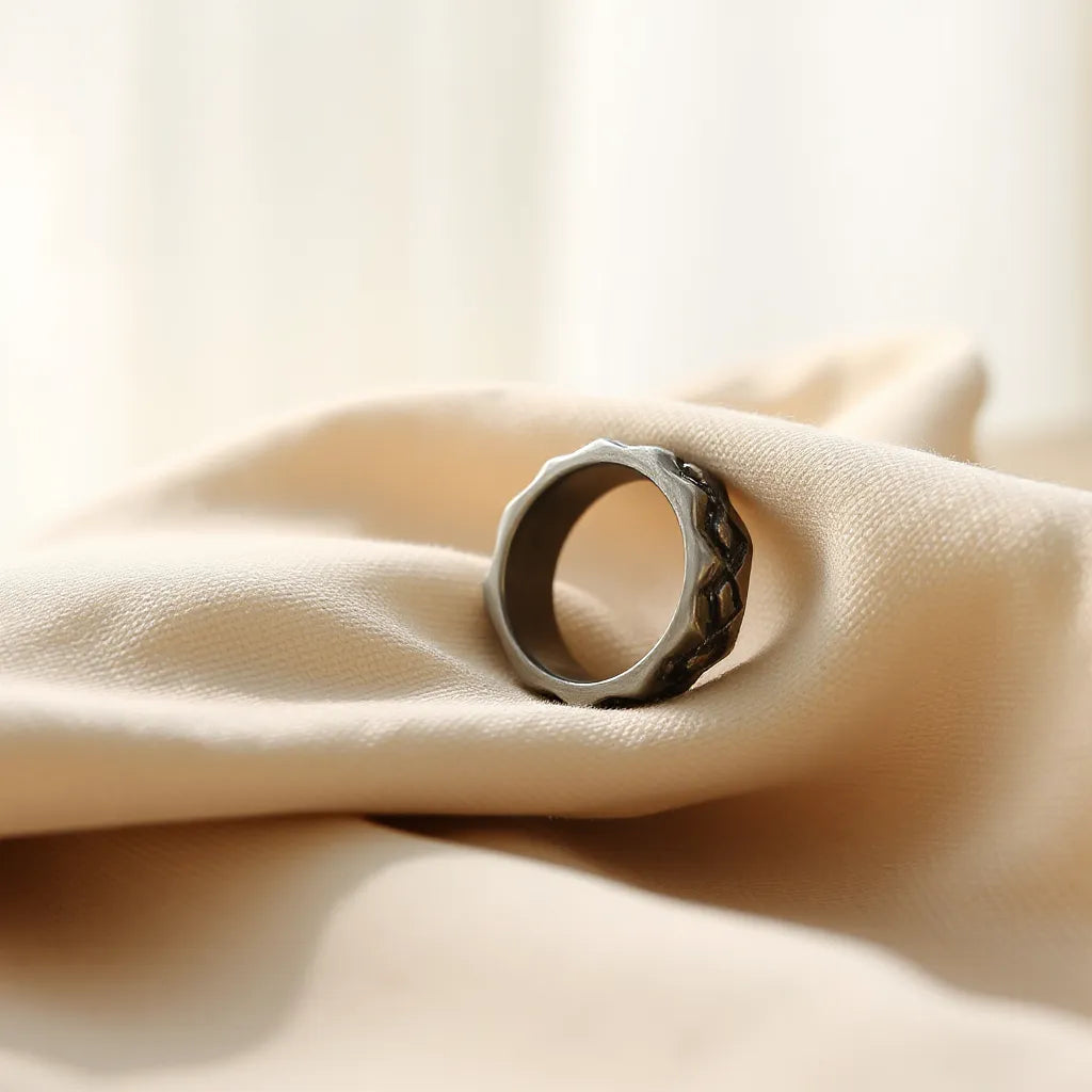Unique design ring with sculpted metal band and reflective stone in soft natural light