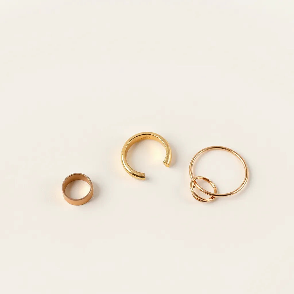 Gold adjustable ring with an open band on a neutral background, shown with subtle jewelry accents