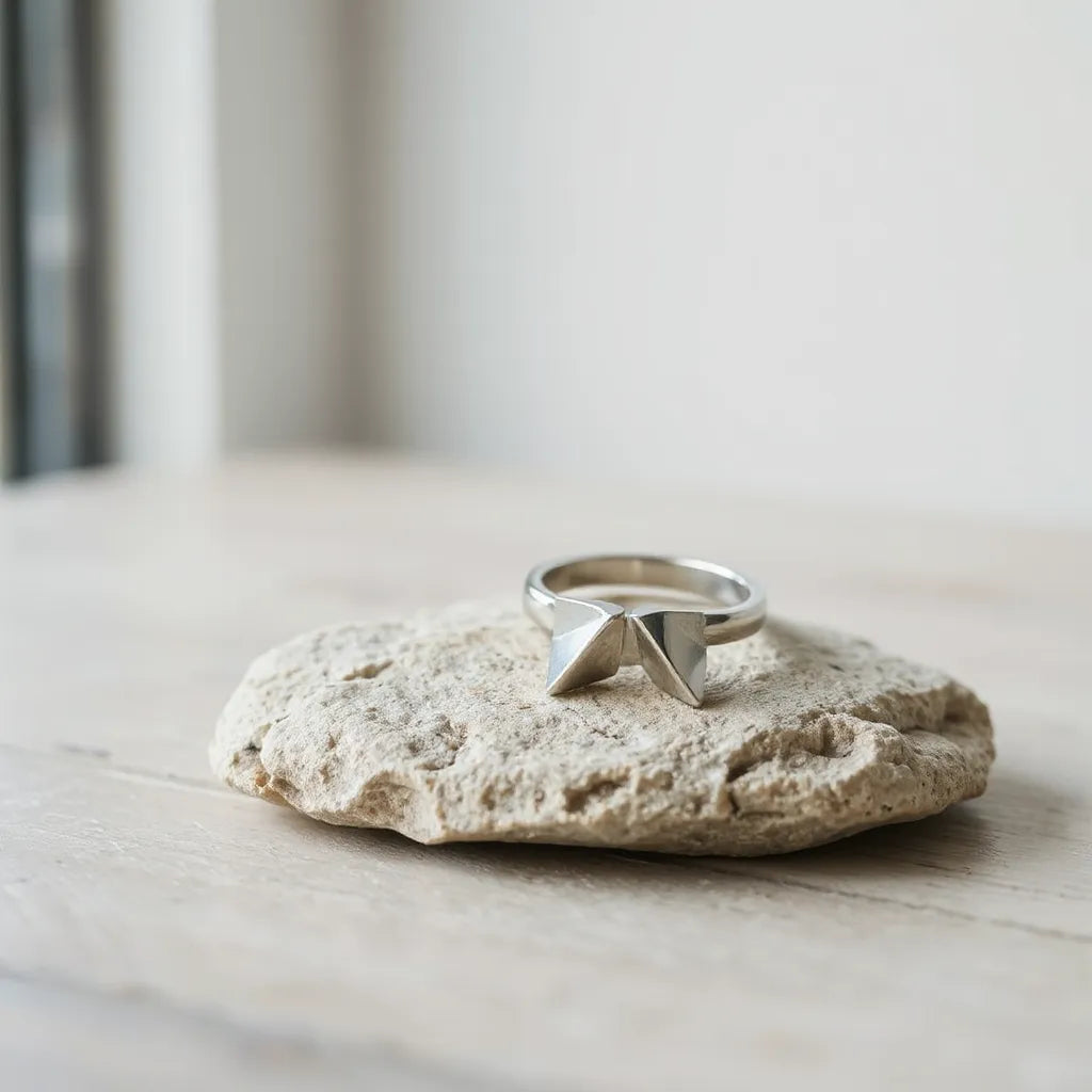 Asymmetric geometric ring with angular facets displayed on a neutral stone surface under soft natural light