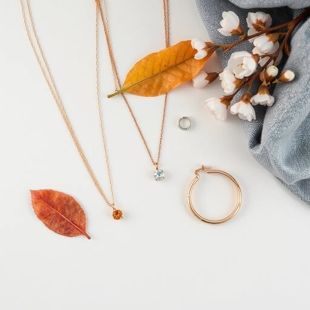 Layered necklaces, earrings, bracelet, and ring arranged with subtle seasonal accents on a neutral background