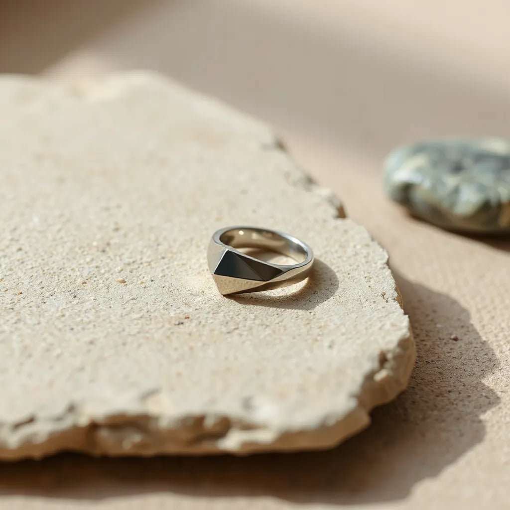Geometric design ring with angular facets on a neutral stone surface in soft natural light