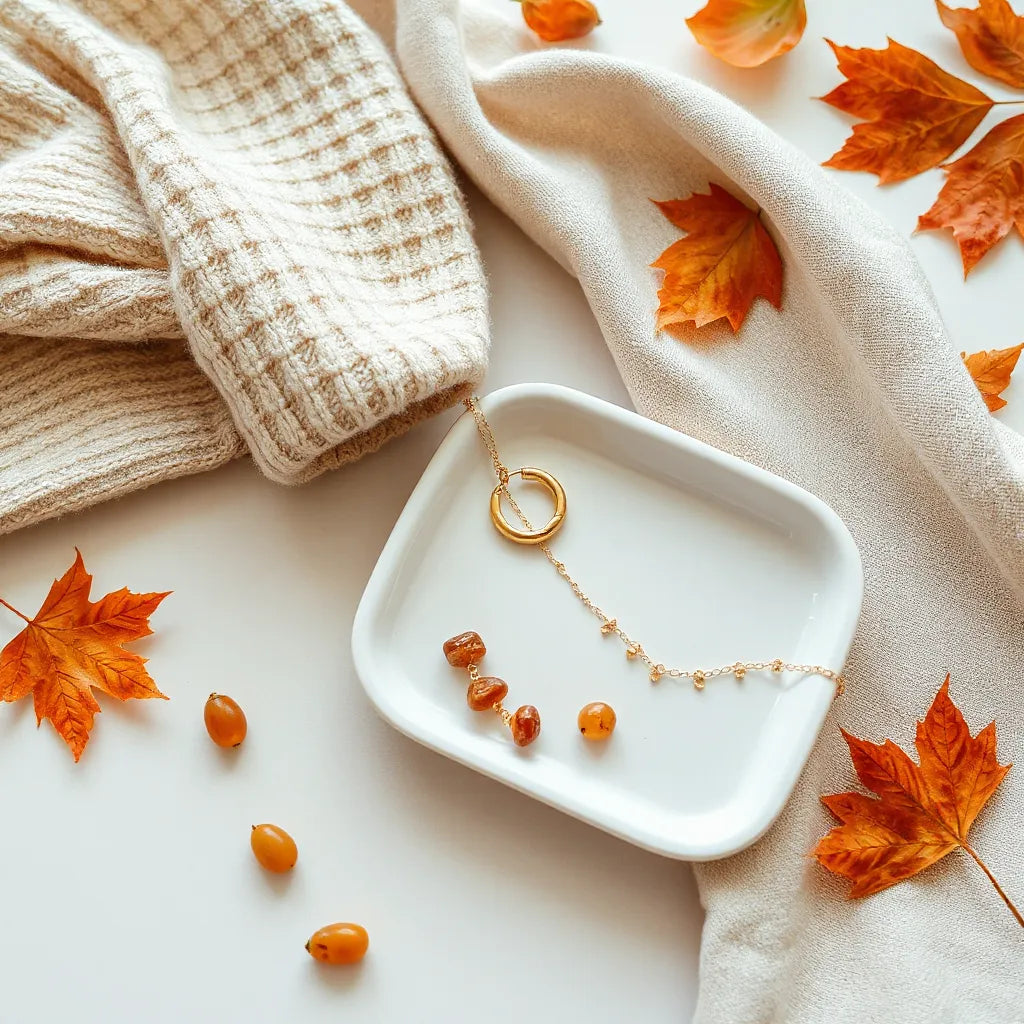 Layered gold-toned autumn jewelry on a warm knit sweater with amber stones under soft light