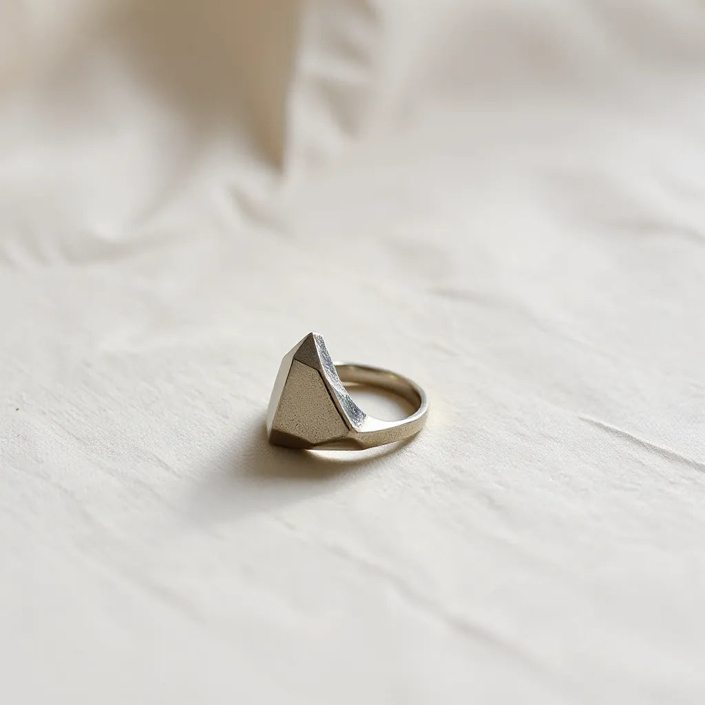 Irregular geometric ring with asymmetrical facets resting on neutral fabric